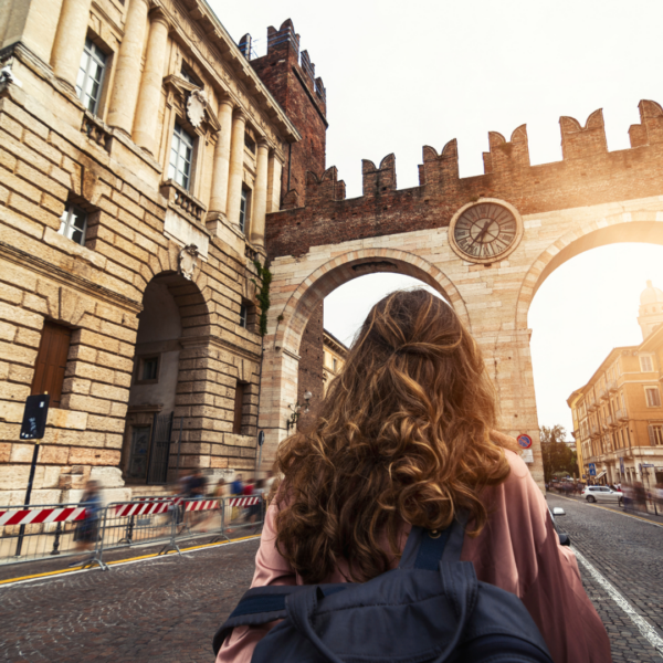 Mujer viajera caminando por una puerta histórica de Verona.