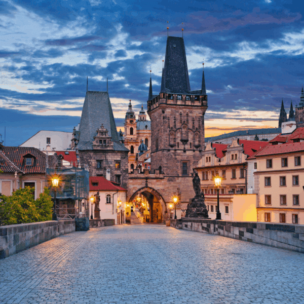 Puente de Carlos en Praga iluminado al atardecer con sus torres góticas.